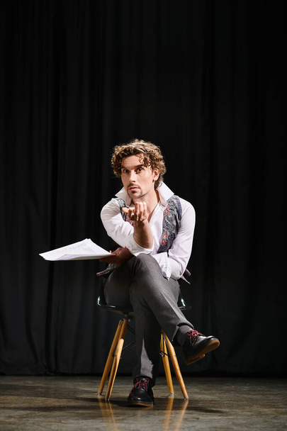 Ένας άνθρωπος κάθεται σε μια καρέκλα, βαθιά στη σκέψη, κρατώντας ένα κομμάτι χαρτί. - Φωτογραφία, εικόνα