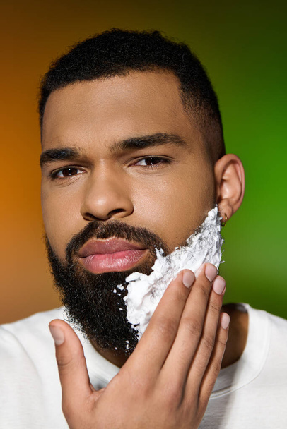 Молодой человек бреет лицо в рамках программы по уходу за кожей.. - Фото, изображение