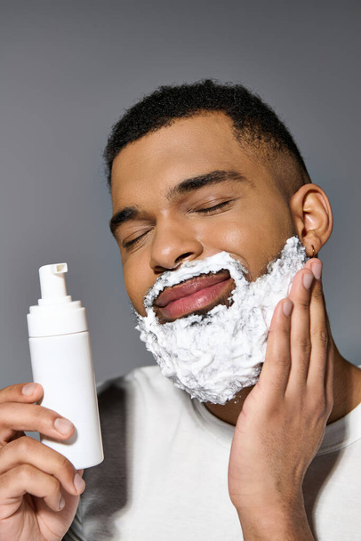 Afrikai-amerikai jóképű fiatalember óvatosan borotválja az arcát.. - Fotó, kép