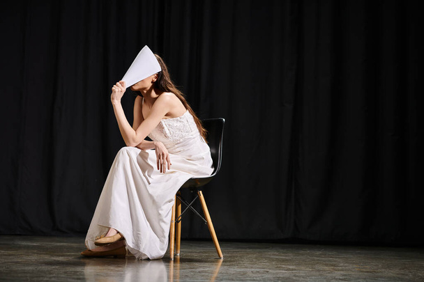 Anmutige Frau im weißen Kleid sitzt auf Stuhl. - Foto, Bild