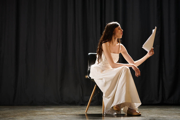 Anmutige Frau im weißen Kleid sitzt elegant auf einem Stuhl. - Foto, Bild