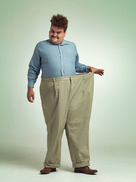 ハッピーマン,肖像画,およびスタジオの背景に減量,測定または腰のためのズボン付きのサイズ. 健康的な食事,肥満,またはモックアップスペースの太りすぎの服のための笑顔の男性. - 写真・画像