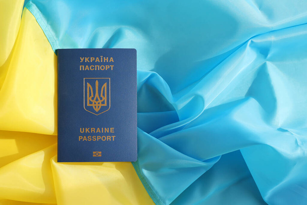 Jeden ukraiński paszport biometryczny na składanej fladze falującej Ukrainy kraju zbliżyć - Zdjęcie, obraz