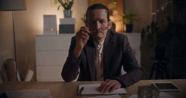 Portret zmartwionego starszego biznesmena zdejmującego okulary siedząc przy biurku późną nocą w biurze - Materiał filmowy, wideo