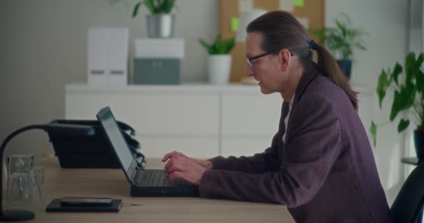 Lockdown shot van senior mannelijke ondernemer typen op laptop op kantoor in het bedrijfsleven - Video