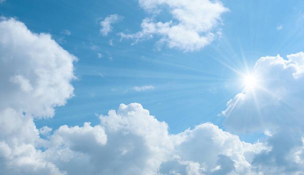 Κάτω προς τα πάνω άποψη του μπλε ουρανού με λαμπερό ήλιο. Λευκά χνουδωτά σύννεφα σε έναν γαλάζιο ουρανό την άνοιξη. - Φωτογραφία, εικόνα