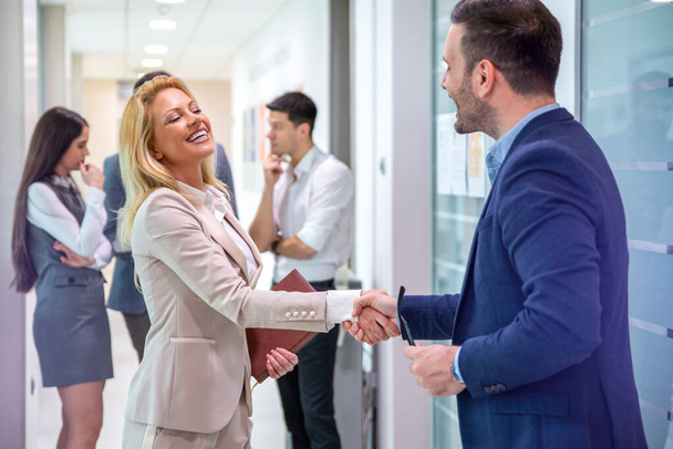 Happy male company director, delighted to meet his new female colleague, greeting attractive blond haired lady to his business team. Handshake and new employee concept. - Photo, Image