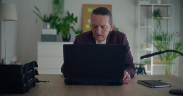 Κλείδωμα shot του ανώτερου ανδρικού επιχειρηματία χρησιμοποιώντας φορητό υπολογιστή στο γραφείο στο χώρο εργασίας των επιχειρήσεων - Πλάνα, βίντεο