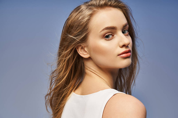 A young, blonde woman exudes grace in a white top, showcasing her flowing long hair in a studio setting. - Photo, Image