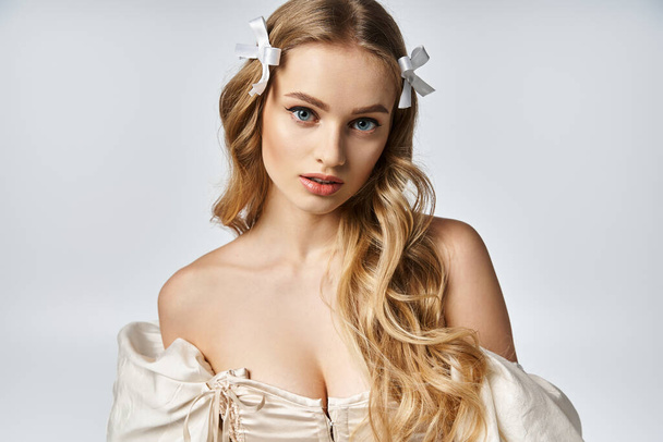 Молодая блондинка излучает элегантность в белом платье, ее длинные волосы каскадом вниз. - Фото, изображение