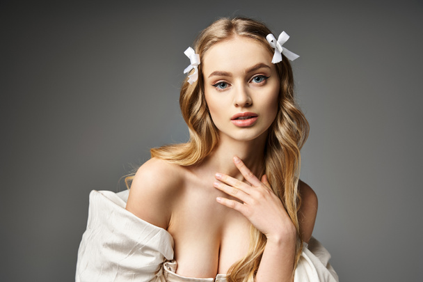 Eine junge und schöne blonde Frau posiert elegant in einem weißen Kleid, das Anmut und Weiblichkeit ausstrahlt. - Foto, Bild