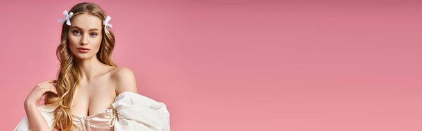Eine atemberaubende junge Frau mit langen blonden Haaren posiert elegant in einem weißen Kleid in einem Studio-Setting. - Foto, Bild
