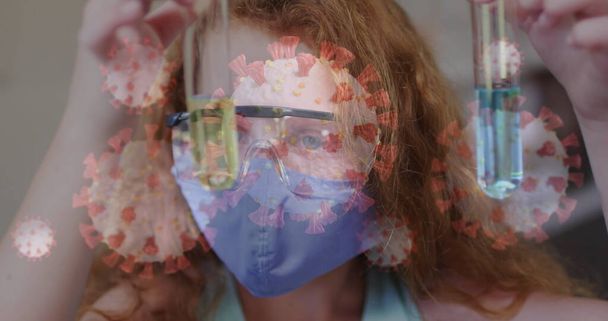 Image of covid 19 cells and schoolgirl in science class wearing face mask. healthcare and protection during coronavirus covid 19 pandemic, digitally generated image. - Fotó, kép