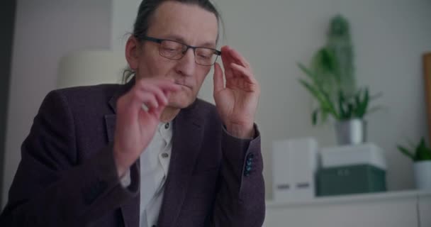 Masentunut vanhempi liikemies riisuu silmälasit yrityksen toimistossa - Materiaali, video