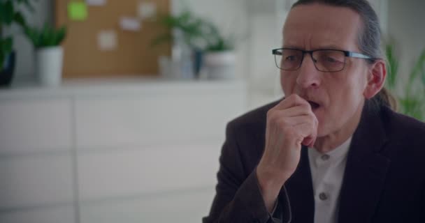 Ernsthafter männlicher Senior-Unternehmer denkt während er im Büro sitzt - Filmmaterial, Video
