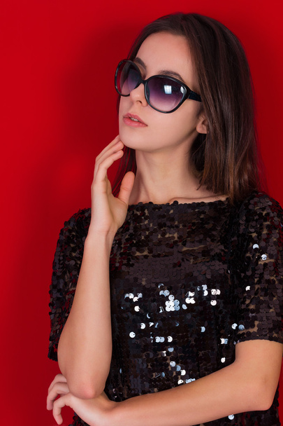 Beautiful brunette girl in a black dress and sunglasses. Brunette with long black hair - Фото, изображение