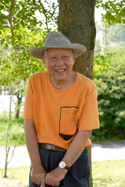Ένας γέρος Ασιάτης επισκέπτεται με χαρά το πάρκο. - Φωτογραφία, εικόνα