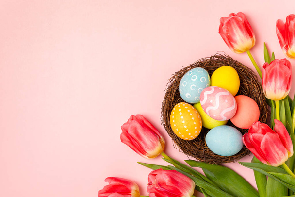 Velikonoční vajíčka s kyticí tulipánů na jasném pozadí. Velikonoční oslavy. Barevné velikonoční ručně zdobené velikonoční vajíčka. Místo pro text. Kopírovat prostor. - Fotografie, Obrázek