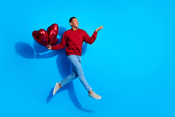 Full length profile portrait of handsome man jump arm hold balloons empty space isolated on blue color background. - Foto, immagini
