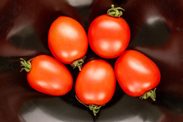Siyah seramik tabakta birkaç domates, makro, üst manzara.. - Fotoğraf, Görsel