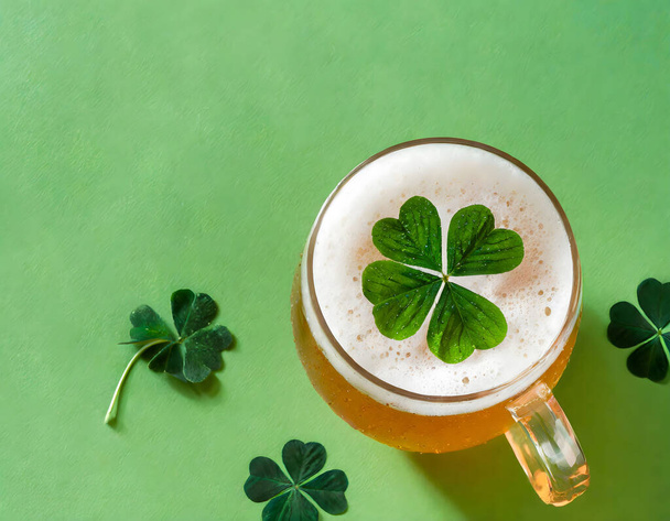 Sklenice piva s jetelem, obklopená dalšími hřebíčky, na zeleném pozadí, symbolizující oslavu svatého Patricka - Fotografie, Obrázek