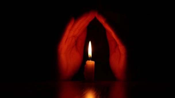 Γυναικεία χέρια κοντά σε μια φλόγα κεριού στο σκοτάδι, την πίστη και τη θρησκεία, προσεύχονται - Πλάνα, βίντεο