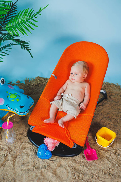 Ένα μωρό είναι ξαπλωμένο σε μια ξαπλωμένη καρέκλα για μωρά. Παιδική ψυχαγωγία. - Φωτογραφία, εικόνα