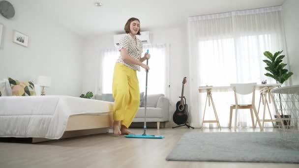 Fehér házvezetőnő felmossa a padlót, miközben élénk hangulatban táncol a modern lakásban. Boldog energikus anya vagy tisztább élvezze a takarítás a nappaliban, miközben a zene. Életstílus. Pedagógia. - Felvétel, videó