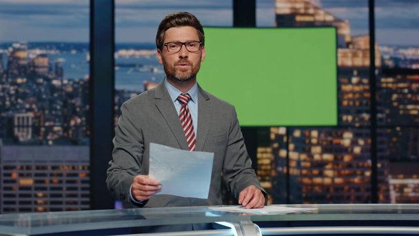 News announcer showing mockup screen reporting breaking news in tv channel studio. Positive presenter in formal suit talking about daily events pointing chromakey monitor. Television industry concept - Photo, image
