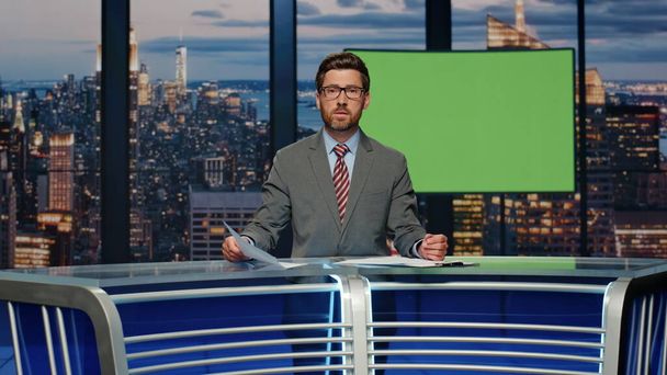 Reporter man talking chromakey screen placeholder at studio. Professional presenter sitting in television newsroom channel reporting live news. Handsome anchor in formal suit broadcasting mockup tv - Valokuva, kuva