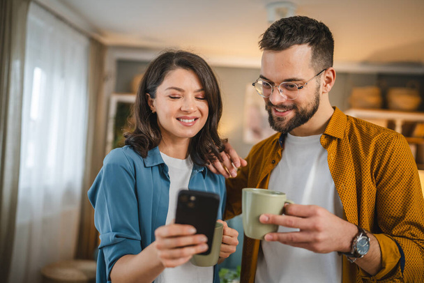 Aikuinen pari mies ja nainen aviomies vaimo on kuppi kahvia käyttää matkapuhelimen haku internet sosiaalinen verkosto onnellinen hymy - Valokuva, kuva