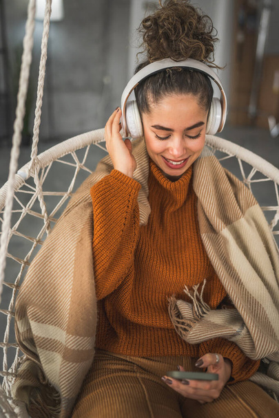 Evde kulaklıklı bir kadın müzik dinliyor, mutlu bir gülümseme. - Fotoğraf, Görsel