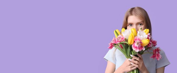 Hübsche junge Frau mit einem Strauß schöner Tulpen auf fliederfarbenem Hintergrund mit Platz für Text - Foto, Bild