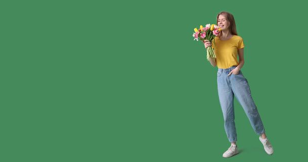 Mooie jonge vrouw met boeket van mooie tulpen op groene achtergrond met ruimte voor tekst - Foto, afbeelding