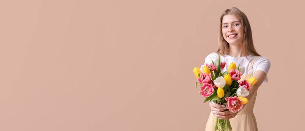 Pretty young woman with bouquet of beautiful tulips on beige background with space for text - Photo, Image