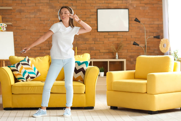 ヘッドフォンの若い女性が自宅で休日に踊る - 写真・画像
