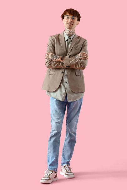 Όμορφος νεαρός επιχειρηματίας με τατουάζ σε ροζ φόντο - Φωτογραφία, εικόνα