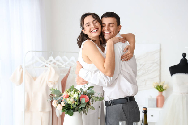 Молода пара з весільним букетом обіймає в офісі - Фото, зображення