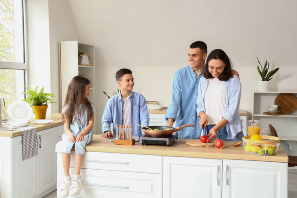 Kleine kinderen met hun ouders koken in de keuken - Foto, afbeelding