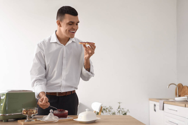 Genç adam kahvaltıda tatlı reçelli tost yiyor. - Fotoğraf, Görsel