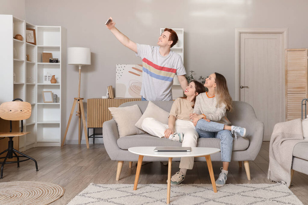 Nuoret ystävät ottavat selfie sohvalla olohuoneessa - Valokuva, kuva