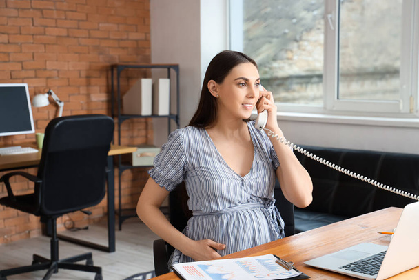 Вагітна бізнес-леді розмовляє по телефону в офісі - Фото, зображення