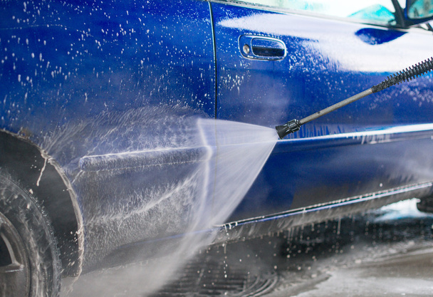 Kék autómosó nagynyomású vízsugár segítségével. - Fotó, kép
