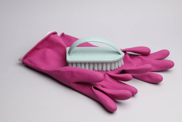 Accessoires voor reiniging. Handschoenen en borstel op grijze achtergrond. - Foto, afbeelding