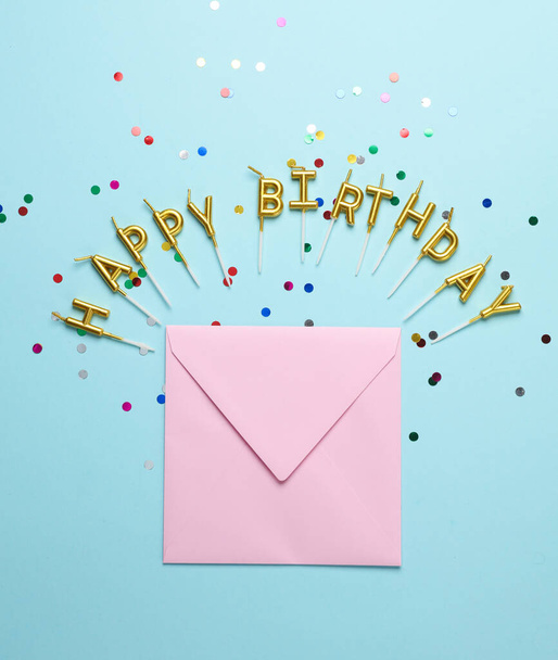 Velas doradas letras en forma de palabra feliz cumpleaños con sobre sobre sobre fondo azul - Foto, Imagen