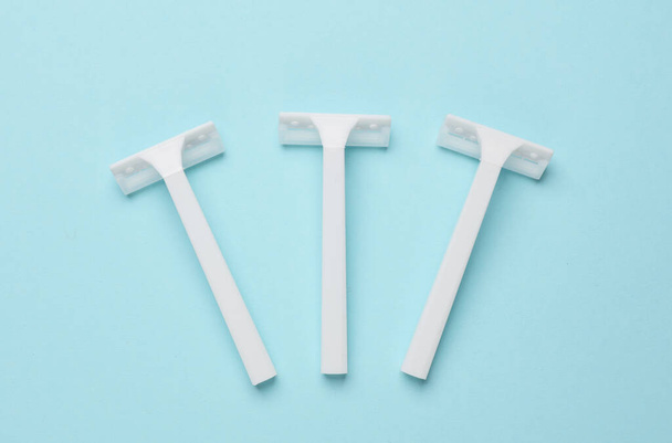 Disposable white plastic razors on blue background. Top view - Photo, Image