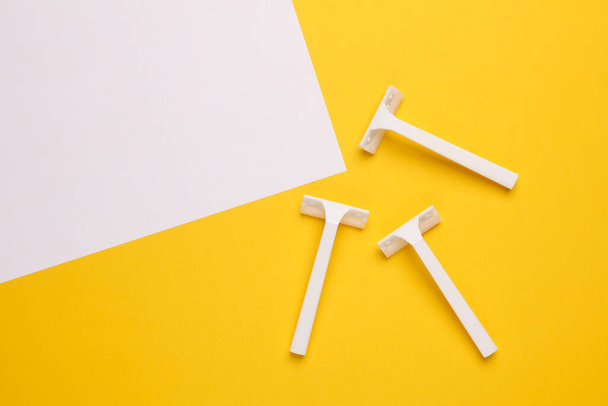 Λευκό πλαστικό ξυραφάκι μίας χρήσης σε κίτρινο λευκό φόντο. Άνω όψη - Φωτογραφία, εικόνα