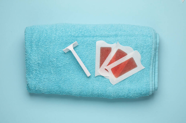 Tiras de cera para depilación y maquinillas de afeitar en toalla. Concepto de belleza. Vista superior - Foto, imagen