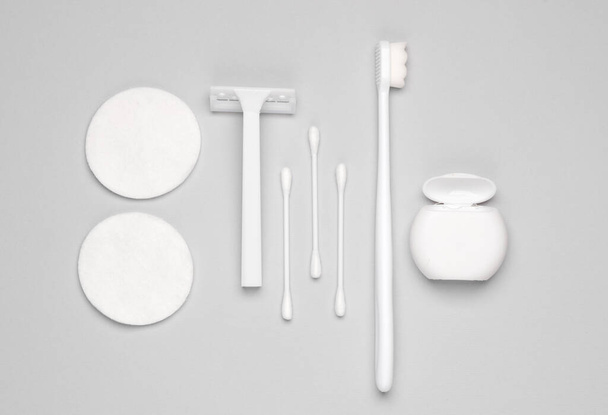Hygiene products. Razor, dental floss, toothbrush, cotton buds and pads on a gray background. Flat lay - Photo, Image