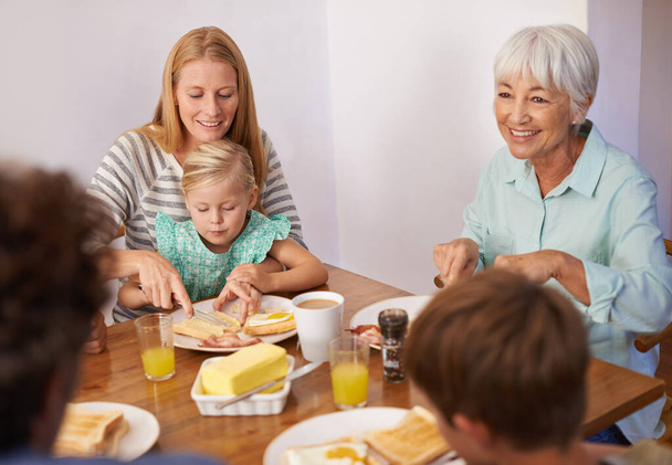 Perhe, lapset ja aamiainen ruokaa isoäidin terveellistä ravitsemusta ateria, hyvinvointi tai liimaus. Naiset, syöminen ja tytär lounaspöydässä asunnossa aamulla yhteys, brunssi tai nälkä. - Valokuva, kuva